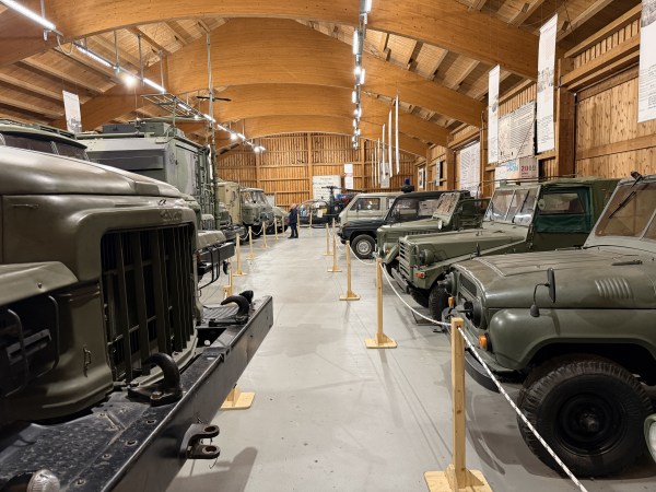 Vojenská vozidla ve vojenské zelené barvě v hale pro vozidla s dřevěnou střechou a dřevěnými stěnami